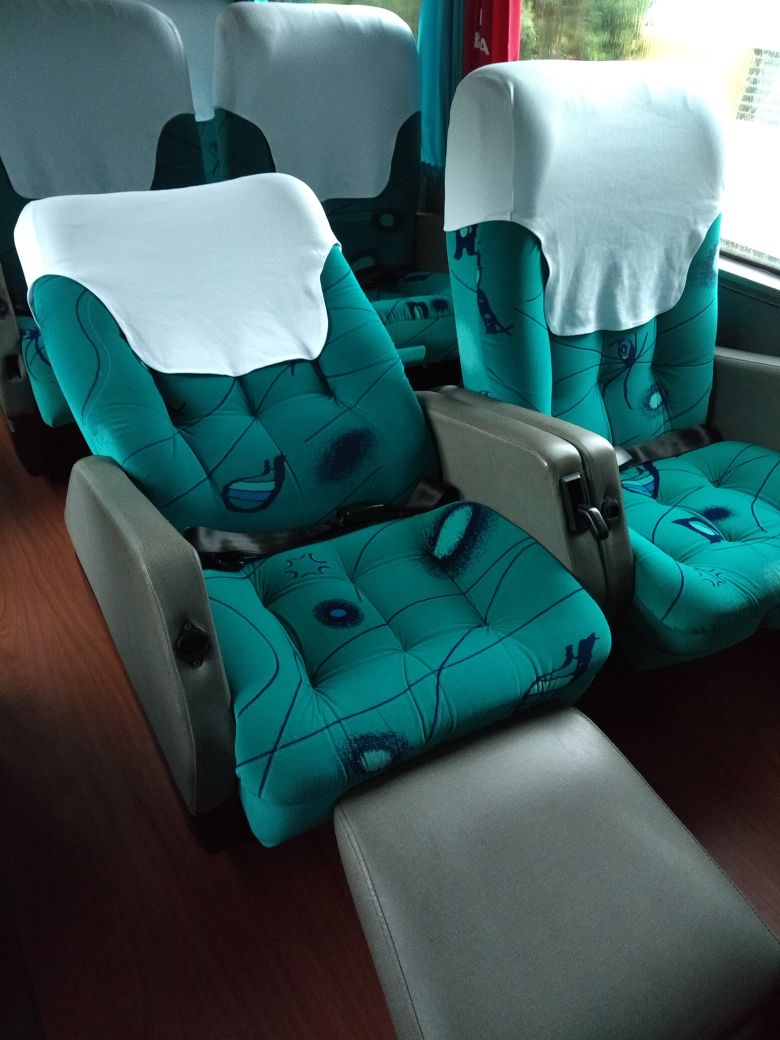 Interior luxuoso de ônibus leito total com poltronas azuis reclináveis, ar condicionado e iluminação suave noturna